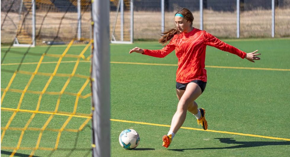 Mujer jugando fútbol en la cancha deportiva de Porto Wayepo.